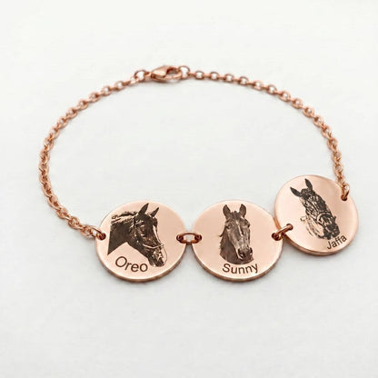 Rose gold bracelet with three circular charms engraved with horse faces and names on a light gray background.