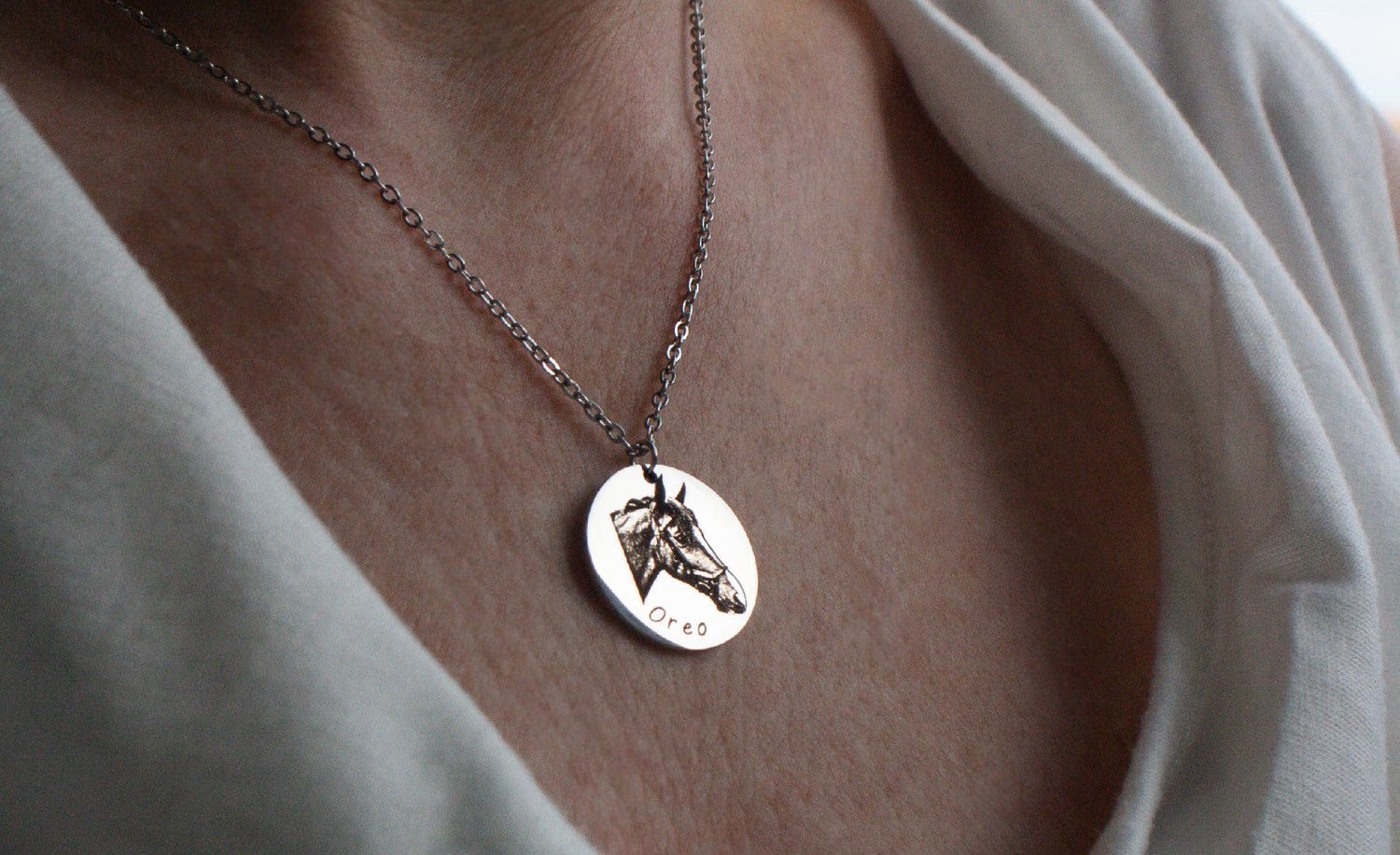 Necklace with a pendant worn by a person in a white shirt