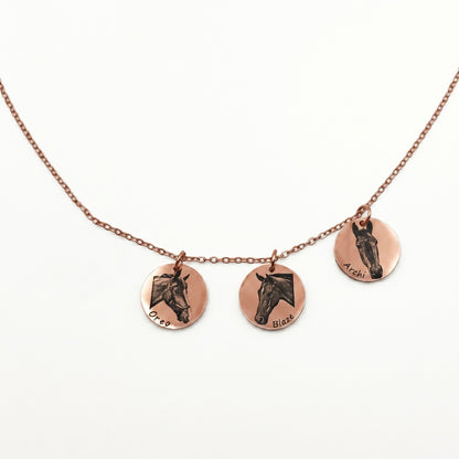 Necklace with three circular rose gold pendants featuring engraved horse faces on a white background