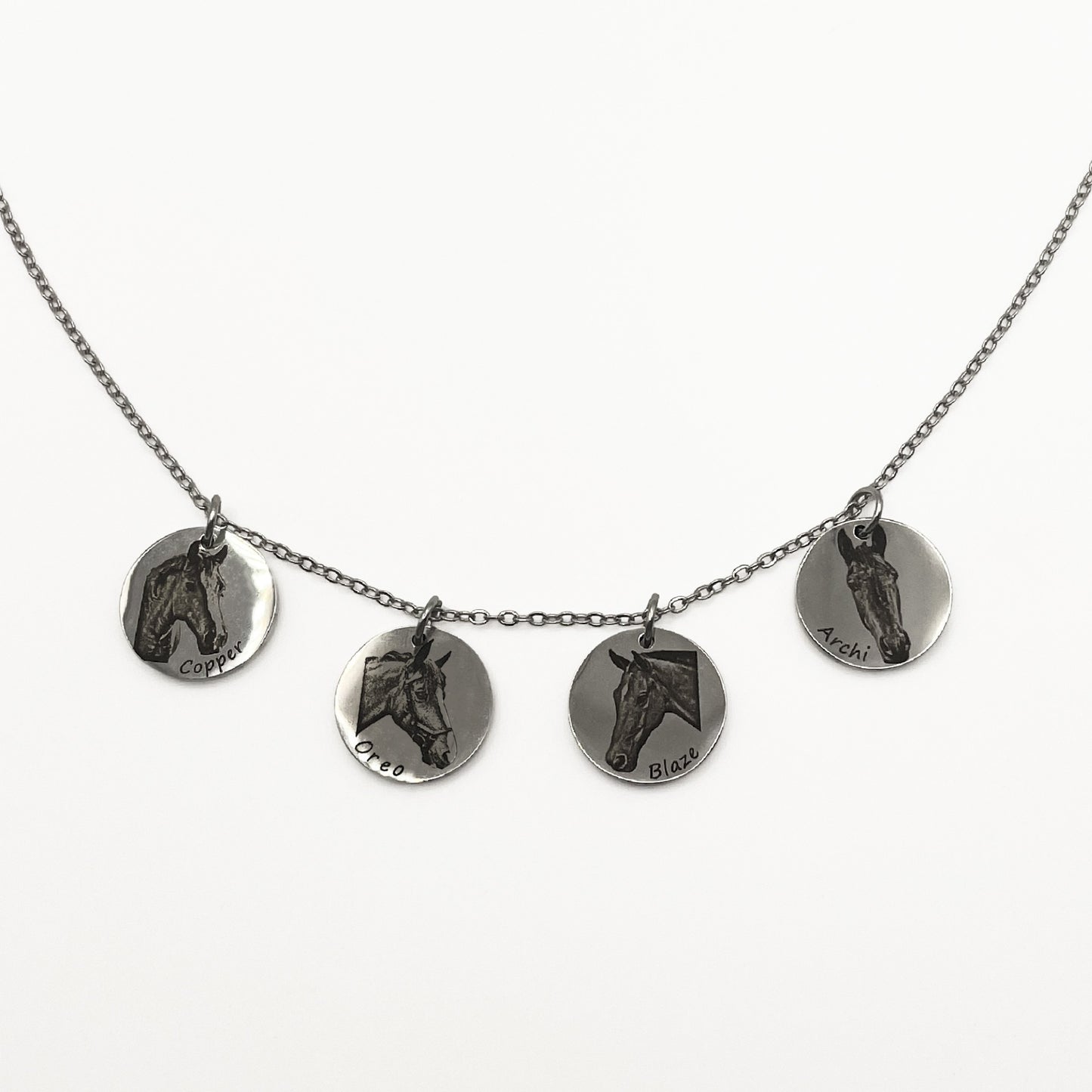 Necklace with four round silver pendants featuring horse faces on a white background